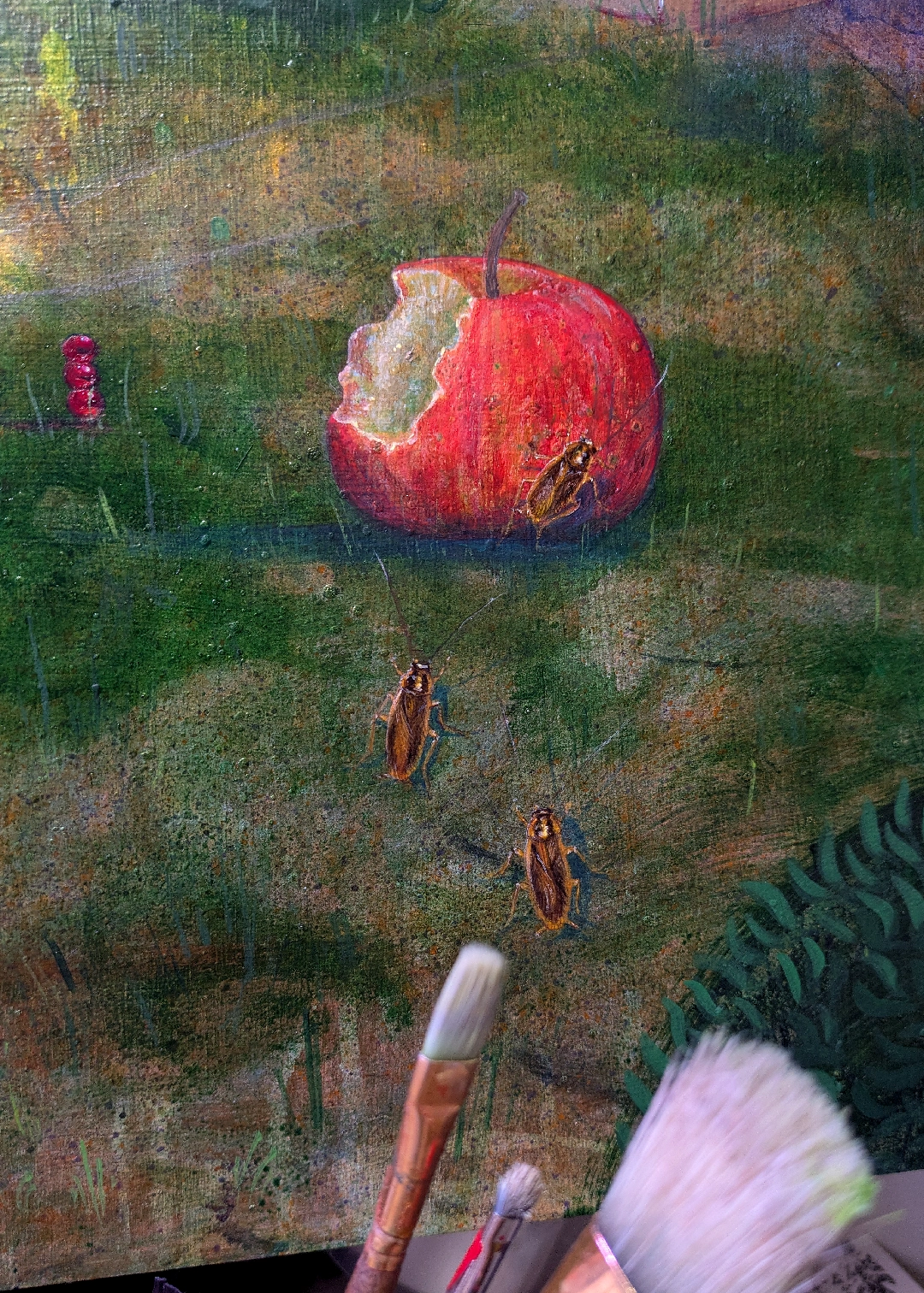 A painting of a half-eaten apple with cockroaches approaching it, sitting on an easel behind actual paintbrushes.